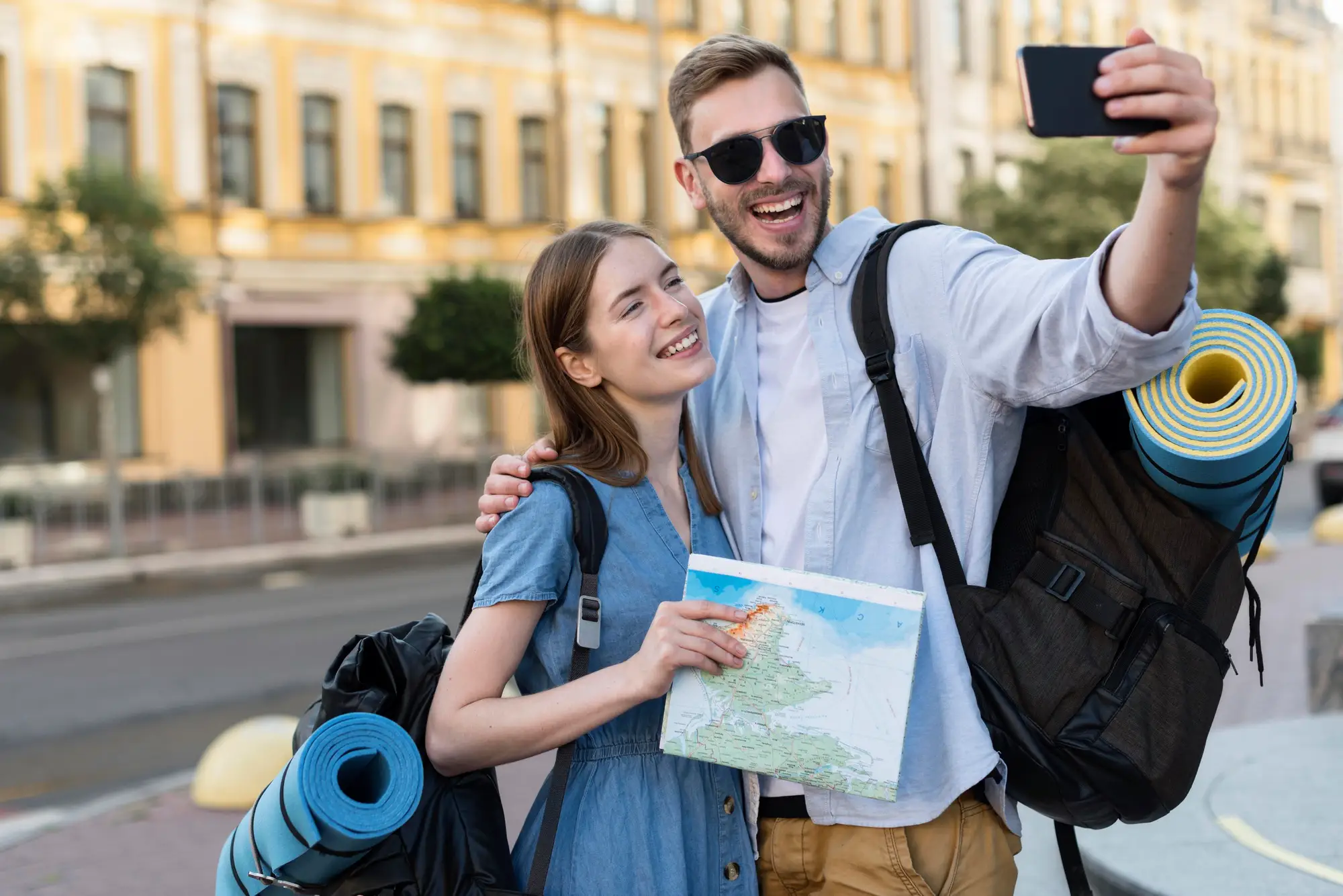 smiley-tourist-couple-taking-selfie-while-carrying-backpacks smiley-tourist-couple-taking-selfie-while-carrying-backpacks